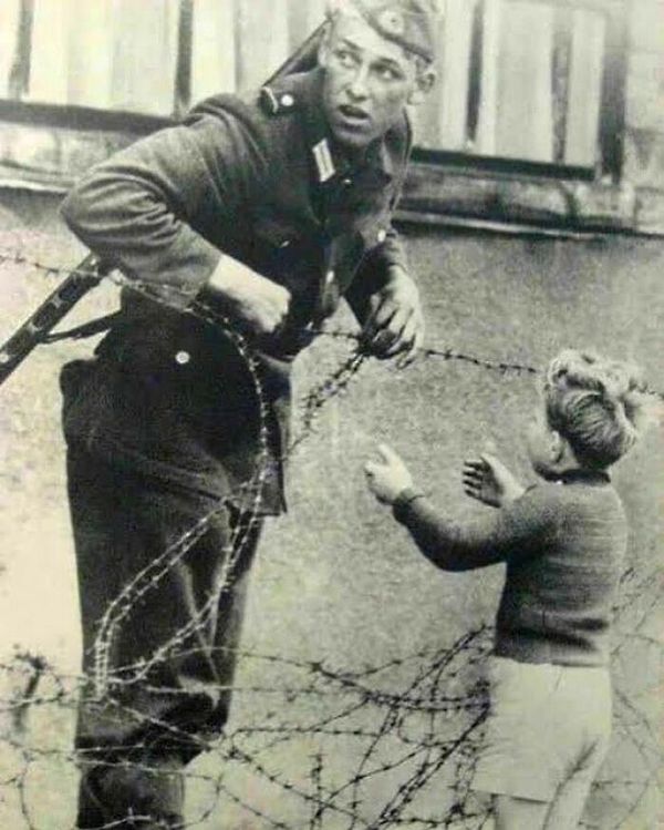 15. Doğu Alman askeri, küçük bir çocuğun Berlin Duvarı'ndan kaçmasına yardım ediyor.