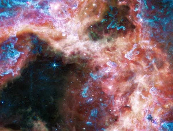 Bulutsunun merkezi, merkezin sağındaki parlak mavi yıldız kümesi tarafından gazdan temizlenmiş şekilde görülüyor.