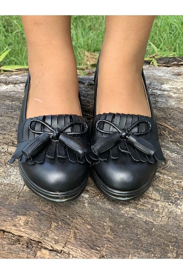3. Kız çocukları için çok sevimli, püskül detaylı siyah bir okul ayakkabısı.