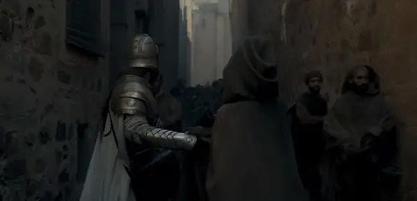 Bir Kingsguard şövalyesi ve kapüşonlu bir kişiyi, King's Landing ara sokağında görüyoruz.