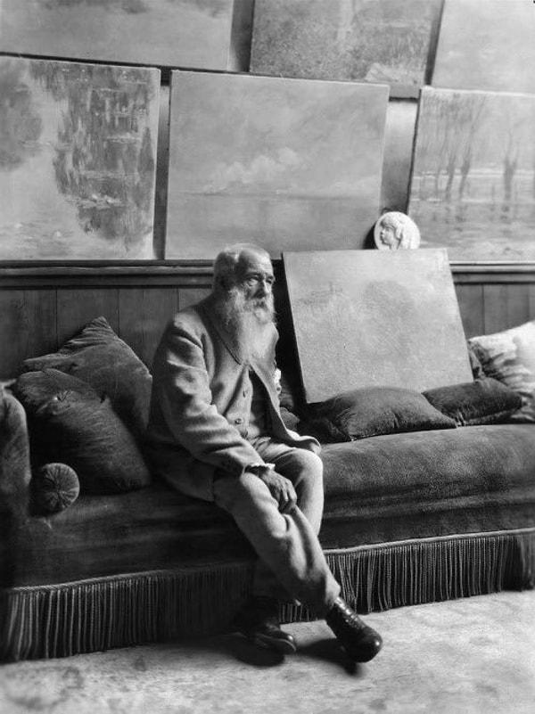 12. Fransız empresyonist ressam Claude Monet, görme yetisinin zayıfladığı kariyerinin sonuna doğru tablolarıyla otururken. (1925)