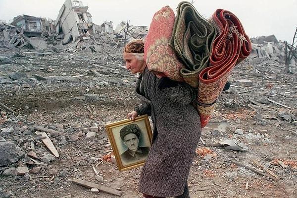 14. Grozni'de yaşlı bir Çeçen kadın sadece kocasının portresi ve kilimleriyle evini terk ediyor. (1995)