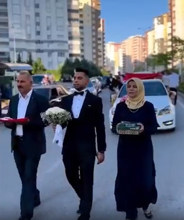 Damadın elinde çiçek gözükürken, anne ve babanın ellerinde ise Türk Bayrağı ve Kur-an gözüküyor.
