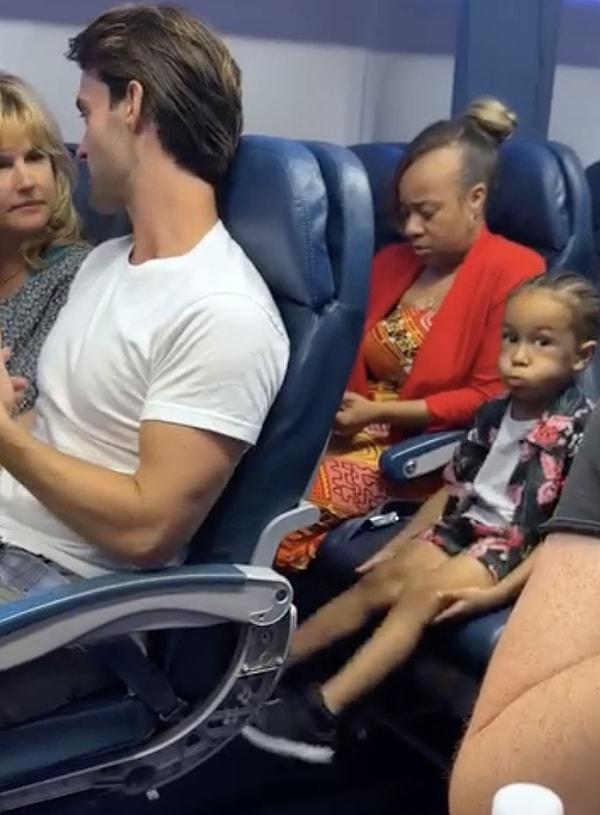 Arkadaki çocuk saatler süren uçuştan sıkılmış olacak ki önünde oturan adamın koltuğunu tekmelemeye başlıyor.