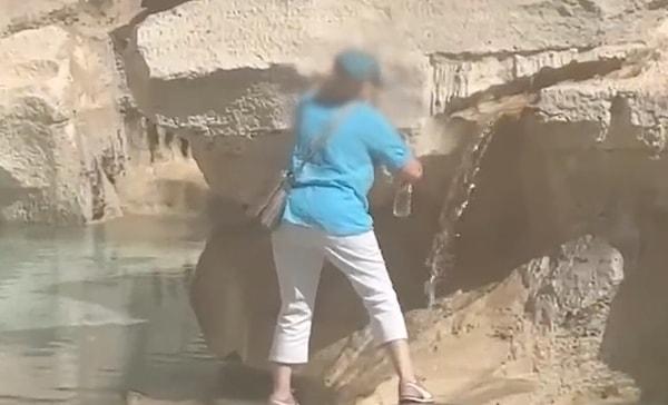 Bir kadın Trevi Çeşmesi'ne tırmanarak, şişesine su doldurdu.