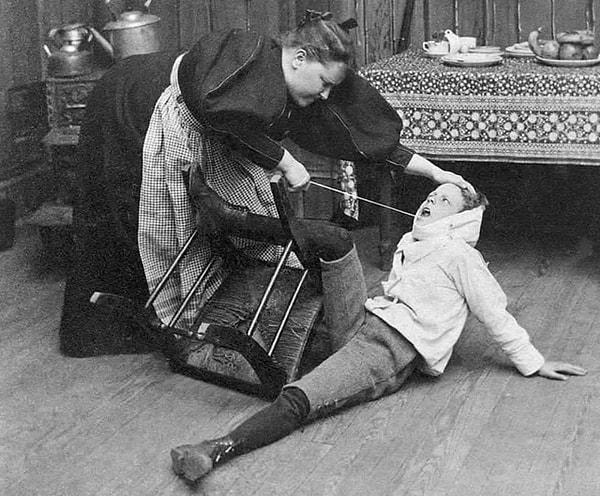 12. Oğlunun sallanan dişini çekmeye yardım eden bir anne. (1897)