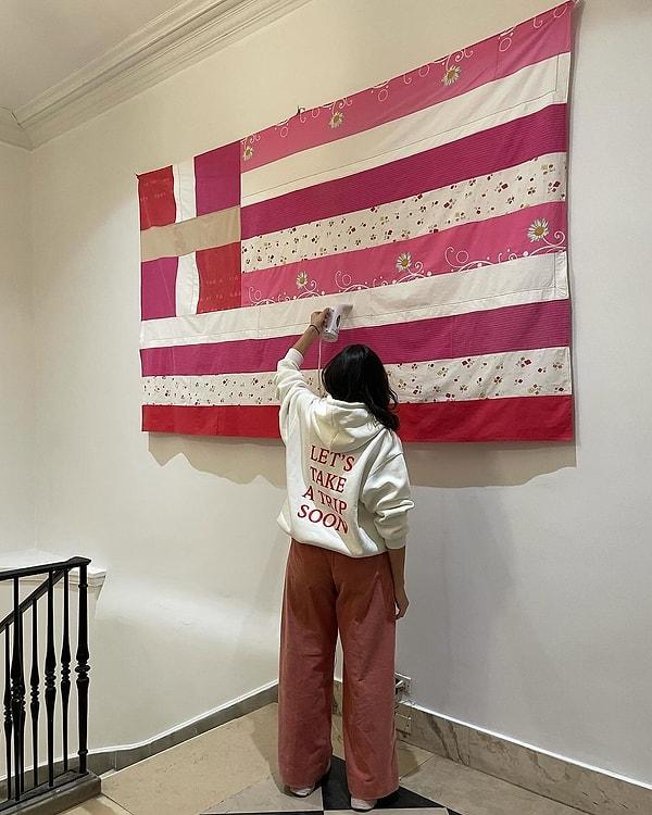 Georgia Lale isimli sanatçı, kadın cinayetlerine dikkat çekmek için Yunan kadınların bağışladığı kumaşlardan açık kırmızı/pembe tonlarını kullanarak Yunanistan bayrağı dikti.