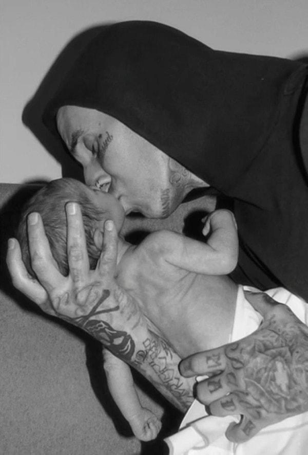 At 48, Travis Barker gently kisses the tiny feet of their baby, capturing a heartwarming moment.