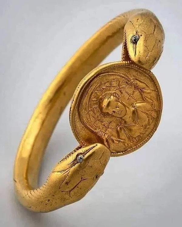 9. Tanrıça Diana'nın madalyonunu tutan cam gözlü iki başlı bir yılanı tasvir eden M.S 1. yüzyıldan kalma altın bileklik.