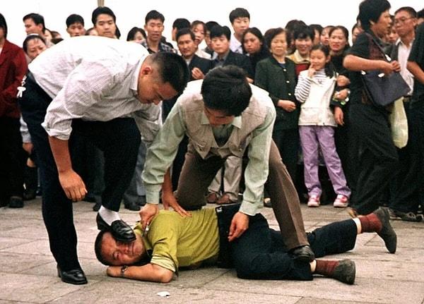 9. 12 Ekim 2000'de Tiananmen Meydanı'nda polis tarafından tutuklanan bir Falun Gong göstericisi. Falun Gong din harekatı yasağını protesto eden en az 300 kişi o gün meydanda tutuklandı ve bu, 1989'dan sonra Tiananmen Meydanı'ndaki en büyük gösteri oldu.