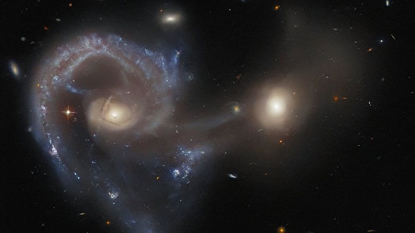 Ayrıca teleskobun sol üst köşesinde daha küçük ve parlak mavi bir sarmal olarak beliren Arp 295c galaksisi de görülüyor.