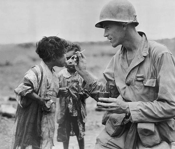 9. Amerikalı bir asker, 1945'te Okinawa adasındaki iki Japon çocuğuyla erzağını paylaşıyor.