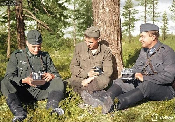 14. Bir arada oturup fotoğrafa olan ilgilerinden bahseden bir Alman, Sovyet askeri ve Fin askeri. (1941, Finlandiya)