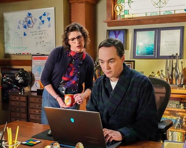 Sheldon ile Amy bilgisayarda bir şeye bakıp gülümsüyorlar. Sheldon'ın ofisinin duvarlarında The Big Bang Theory'nin final sezonunda kazandığı Nobel Fizik Ödülü de dahil sayısız ödül bulunuyor.