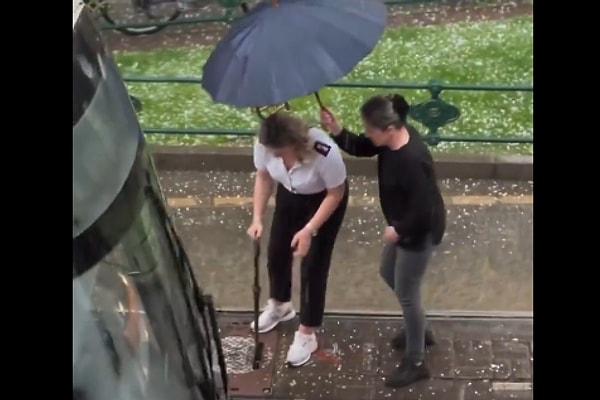 Vatmanı yağmurdan korumak için bir kadın vatandaş ona şemsiyesiyle eşlik etti.