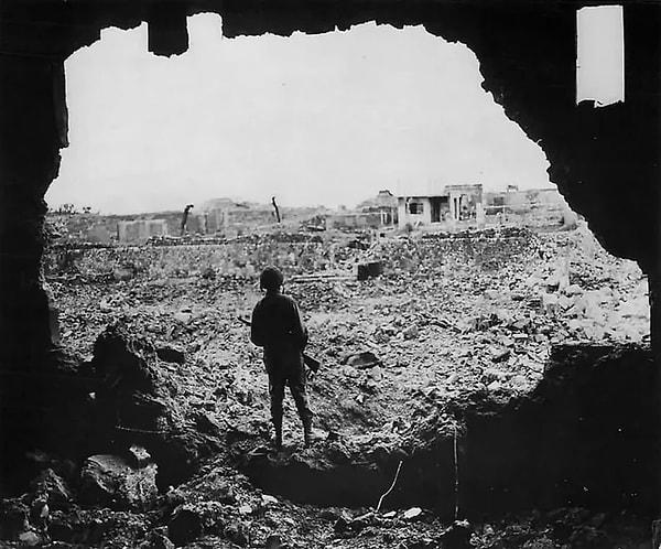 6. Yıkılmış bir binada duran ABD Deniz Piyadesi, Okinawa şehrinin kalıntılarına bakarken çekilmiş bir fotoğraf. (Okinawa Savaşı, 13 Haziran 1945.)