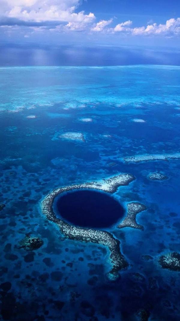Belize'deki Büyük Mavi Delik, dairesel şekli ve koyu mavi rengiyle bilinen dev bir deniz obruğudur.