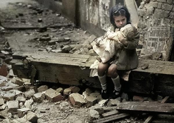 Londra'da bombaların isabet ettiği evinin önünde oturup oyuncağına sarılan kız, tarih 1940