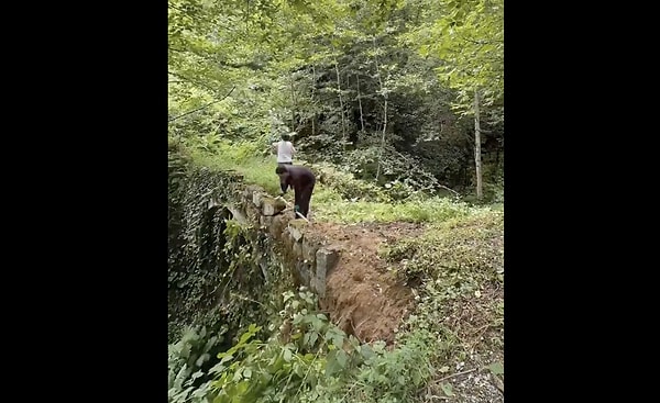 Bir baba ve kızı, tatil için gittikleri Rize'de, yaklaşık 150 yıl önce inşa edilmiş tarihi taş kemer köprüyü el birliğiyle temizledi.