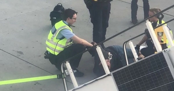 The man was arrested and handcuffed by the police when they boarded the plane, receiving applause from the passengers as he was escorted off.