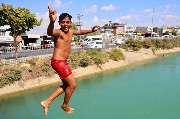 Adana'da nemle birlikte hissedilen sıcaklık 45 dereceyi buluyor. Bunaltıcı sıcaklar nedeniyle bazı öğrenciler okuldan kaçıp sulama kanallarında yüzerek serinlemeye çalışıyor.