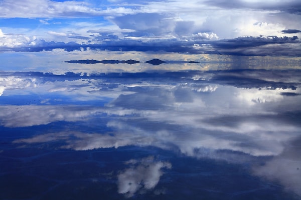 Anlayacağınız, Salar de Uyuni'nin yansıtıcı yüzeyi, tarih öncesi göllerin buharlaşmasıyla oluşan geniş tuz tabakasının, yağışlı mevsimlerde ince bir su tabakasıyla kaplanması sonucu meydana gelir. Bu doğal fenomen, bölgeyi hem bilimsel araştırmalar hem de turizm açısından benzersiz kılmaktadır.