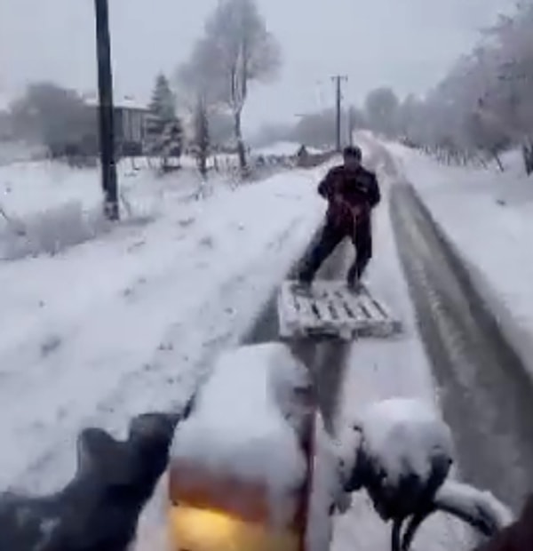 Traktörün arkasına bağladıkları ahşap palet ile Furkan Uygun, Kurudere Mahallesi'nde adeta snowboard yaptı.