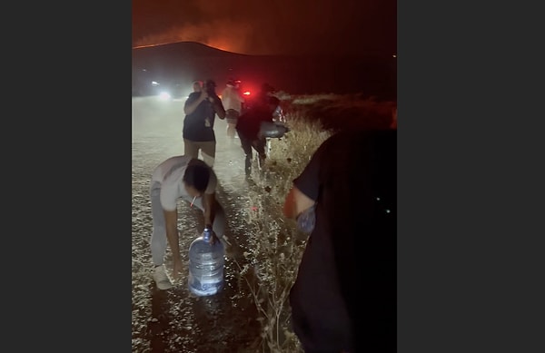 Çeşme’de, yangına müdahale edilmeyen bölgede halk, otluk alanlara damacanalarla su dökerek güvenli alan oluşturmaya çalıştı.