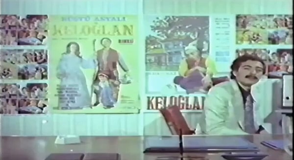Eski film tanıtımında Rüştü Asyalı takım elbisesiyle konuşurken Keloğlan da yanı başında beliriyor.